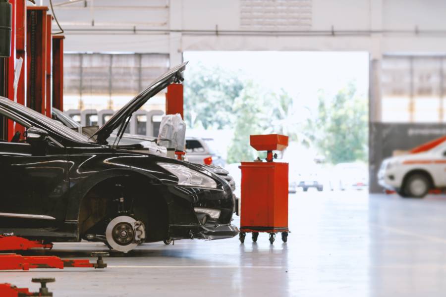 schwarzes Auto mit geöffneter Motorhaube in einer Autowerkstatt