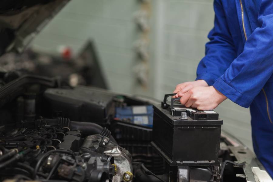 Person in Blaumann arbeitet an Autobatterie